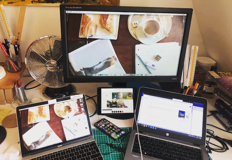 A desk with several computers and phones